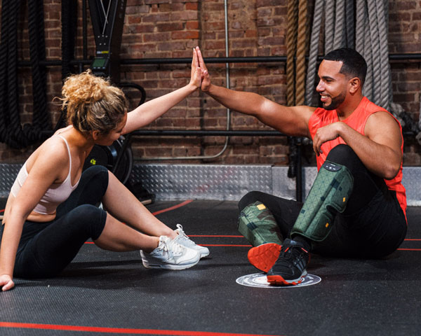 A woman giving a man a high five in a gym