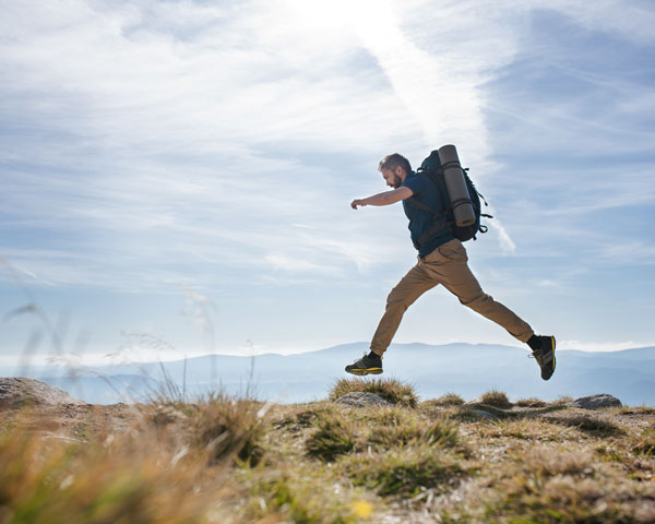 man jumping along hill top