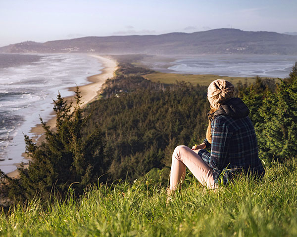 Lady looking out across a coastline from a hill